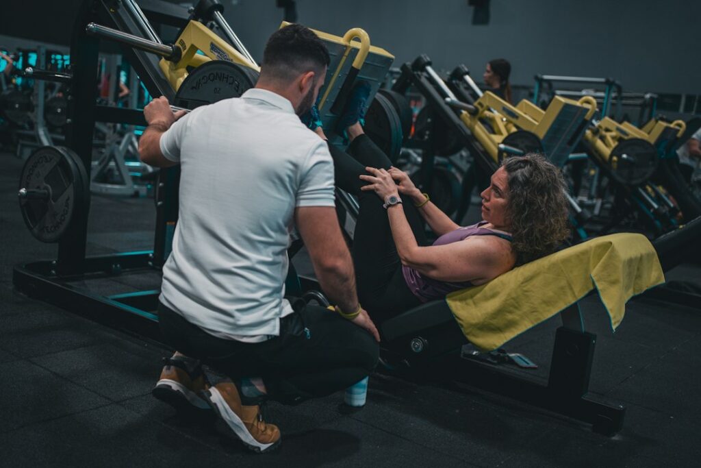 Personal trainer coaching a client during a strength workout. Photo by Sergio Kian on Unsplash.